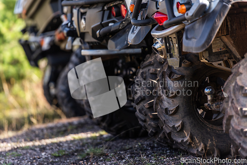 Image of Close-up tail view of ATV quad bike on dirt country road. Dirty wheel of AWD all-terrain vehicle. Travel and adventure concept.