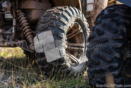 Image of Close-up tail view of ATV quad bike on dirt country road. Dirty wheel of AWD all-terrain vehicle. Travel and adventure concept.