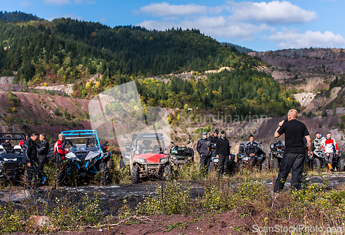 Image of A group of men on a social gathering are preparing to ride an ATV quad bike. People Ride together on a quad atv on muddy forest roads