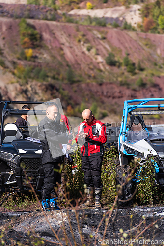 Image of A man in a forest posing next to a quad and preparing for ride