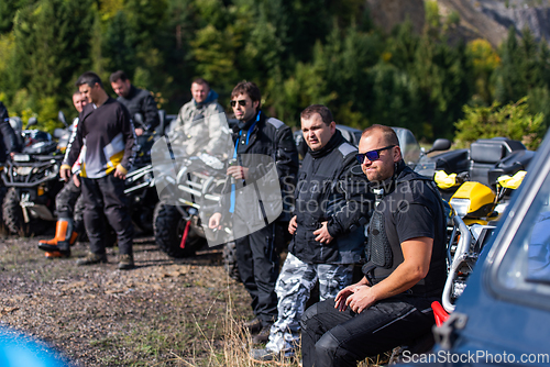 Image of A group of men on a social gathering are preparing to ride an ATV quad bike. People Ride together on a quad atv on muddy forest roads