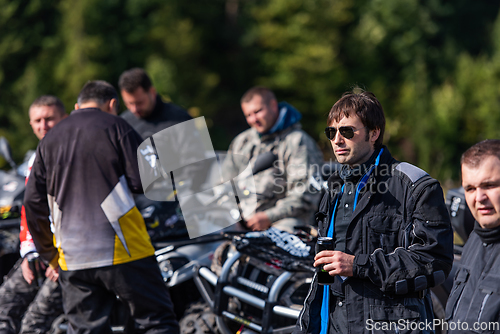 Image of A group of men on a social gathering are preparing to ride an ATV quad bike. People Ride together on a quad atv on muddy forest roads