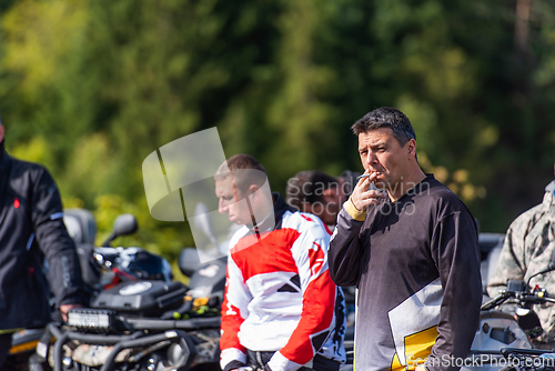 Image of A group of men on a social gathering are preparing to ride an ATV quad bike. People Ride together on a quad atv on muddy forest roads