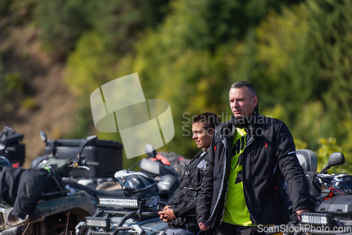 Image of A group of men on a social gathering are preparing to ride an ATV quad bike. People Ride together on a quad atv on muddy forest roads