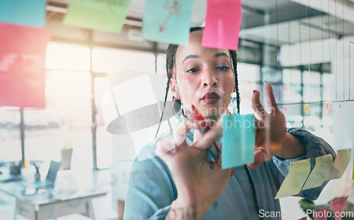 Image of Woman at glass with ideas, thinking and sticky note for business planning, brainstorming or working process. Moodboard, strategy and writing notes for startup proposal on mind map at office workshop.