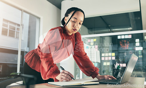 Image of Woman on laptop, research and writing notes, ideas on website for business plan or brainstorming proposal process. Thinking, businesswoman with pen and book on computer, standing in startup office.
