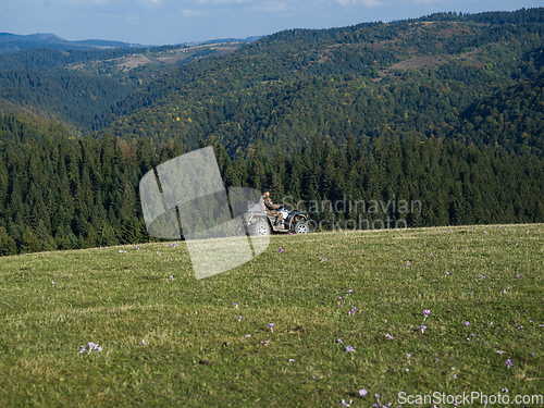 Image of A man driving a quad ATV motorcycle through beautiful meadow landscapes