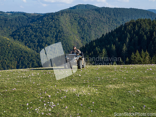 Image of A man driving a quad ATV motorcycle through beautiful meadow landscapes