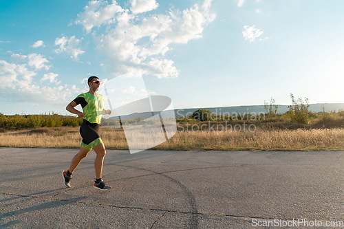 Image of Triathlete in professional gear running early in the morning, preparing for a marathon, dedication to sport and readiness to take on the challenges of a marathon.