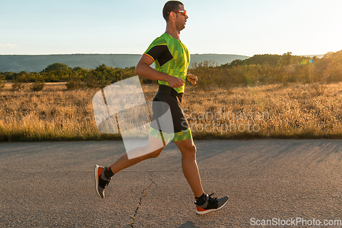 Image of Triathlete in professional gear running early in the morning, preparing for a marathon, dedication to sport and readiness to take on the challenges of a marathon.