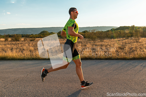 Image of Triathlete in professional gear running early in the morning, preparing for a marathon, dedication to sport and readiness to take on the challenges of a marathon.