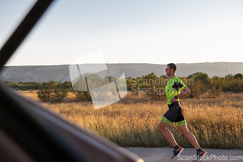 Image of Triathlete in professional gear running early in the morning, preparing for a marathon, dedication to sport and readiness to take on the challenges of a marathon.