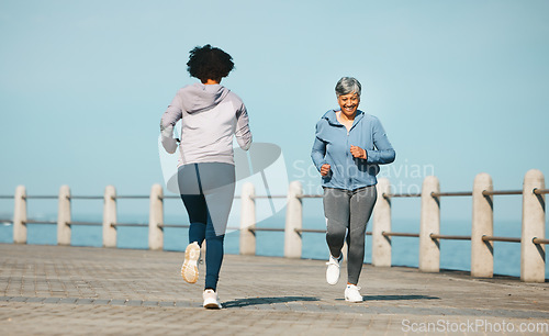 Image of Running, fitness and senior friends by sea with mature women and smile from marathon. Exercise, workout and training on beach promenade path for health and wellness in the morning with happy people