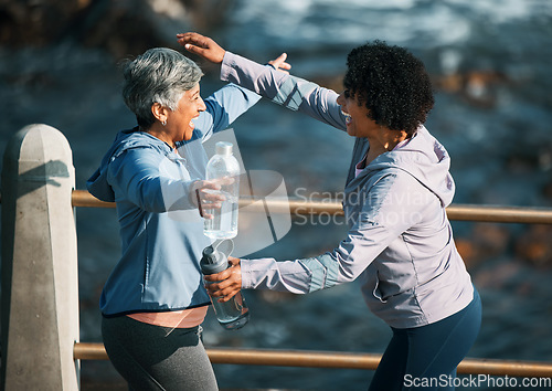 Image of Running, excited hug and women by sea and ocean with love and care for fitness and exercise. Athlete, greeting and mature person with friend on a beach promenade with motivation, embrace and smile
