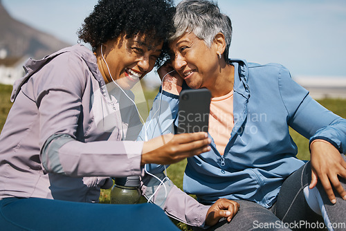 Image of Senior woman, friends and listening to phone with earphones or outdoor for a video call, fitness podcast or announcement. Smile, share and people with headphones at the beach together with smartphone