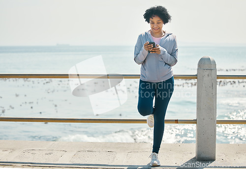 Image of Fitness, beach and woman with a cellphone, typing and social media with network, sports and smile. Happy person, athlete and seaside with a smartphone, internet connection and contact with exercise