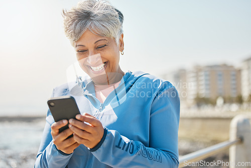 Image of Fitness, beach and senior woman with cellphone, happiness and social media with network, email and smile. Happy person, pensioner and elderly lady with a smartphone, seaside and contact with message