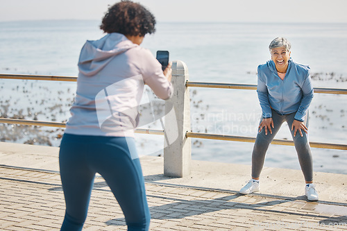 Image of Phone, photograph and friends laugh of senior women at beach with funny joke at sea for fitness. Exercise, mobile and picture for social media post on ocean promenade walk for workout and friendship