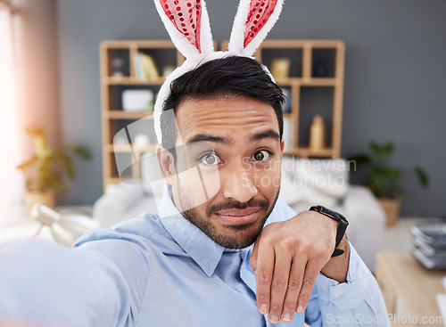 Image of Bunny ears, holiday and selfie with a man and remote work on easter with creative job. Celebration, happy and male professional from Spain feeling silly and goofy with comedy rabbit hat in a home