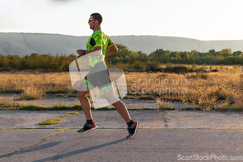 Image of Triathlete in professional gear running early in the morning, preparing for a marathon, dedication to sport and readiness to take on the challenges of a marathon.