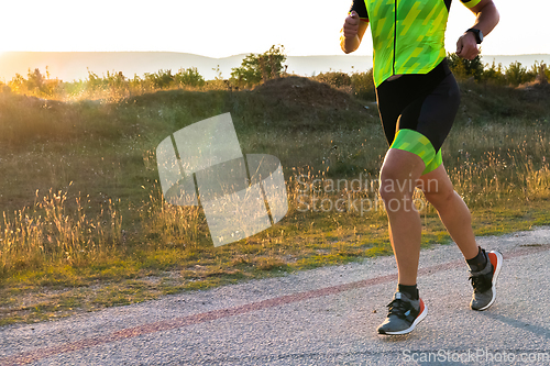 Image of Triathlete in professional gear running early in the morning, preparing for a marathon, dedication to sport and readiness to take on the challenges of a marathon.