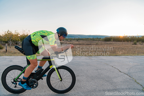 Image of Triathlete riding his bicycle during sunset, preparing for a marathon. The warm colors of the sky provide a beautiful backdrop for his determined and focused effort.