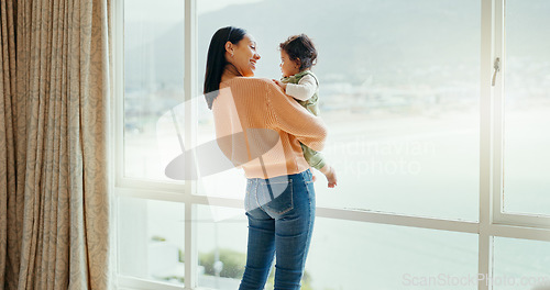 Image of Care, happy and a mother with a baby in a house and looking at the view from a window. Smile, hug and a young mom holding a child for playing, bonding or love together in the morning as family