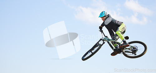 Image of Mountain bike, man and jump in blue sky for competition, freedom or adventure on mockup space. Banner of athlete, sports and bicycle in air for action, cardio race and courage of stunt, speed or risk