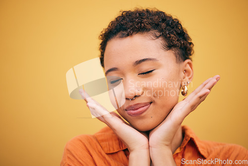 Image of Happy, woman relax and hands on face in studio with smile and confidence feeling cute. Orange background, young and African female person with trendy, modern and student fashion with mockup space