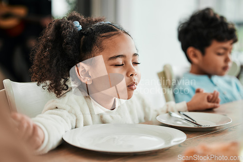 Image of Kids, holding hands and praying at dinner, home and faith for gratitude, solidarity and mindfulness for food. Children, prayer and religion for event, lunch or brunch with eyes closed in family house