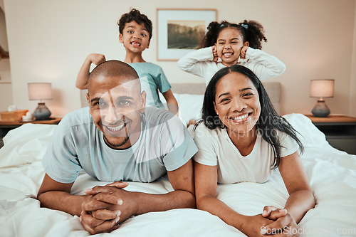 Image of Happy family, portrait and bonding in bed, having fun and playing in their home together. Face, smile and children with goofy, expression and parents in a bedroom playful, games and enjoying weekend