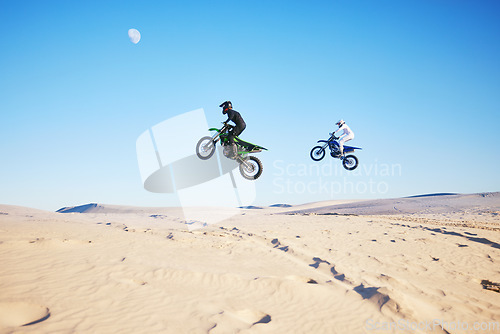 Image of Motorbike, desert race and jump in air for competition, stunt and outdoor for performance, goal and speed. Motorcycle athlete, dunes and ramp in nature, fast or together for contest by sky background