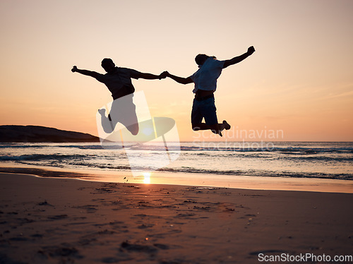 Image of Beach, sunset and silhouette of couple jump, holding hands and enjoy fun quality time together on summer holiday. Energy, ocean sea and excited man, woman or people celebrate Australia vacation