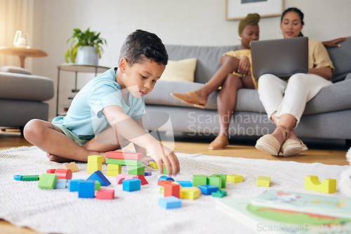 Image of Play, toys and child on floor with parents on sofa for learning, development and education. Lgbtq family, home and boy with building blocks for fun, relax and games with lesbian mothers on laptop