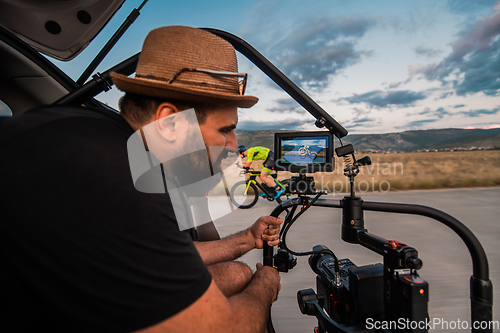 Image of A videographer recording a triathlete riding his bike preparing for an upcoming marathon.Athlete's physical endurance and the dedication required to succeed in the sport.