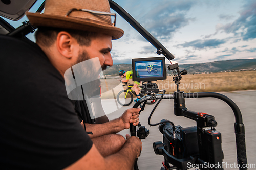 Image of A videographer recording a triathlete riding his bike preparing for an upcoming marathon.Athlete's physical endurance and the dedication required to succeed in the sport.