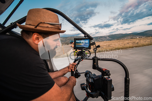 Image of A videographer recording a triathlete riding his bike preparing for an upcoming marathon.Athlete's physical endurance and the dedication required to succeed in the sport.