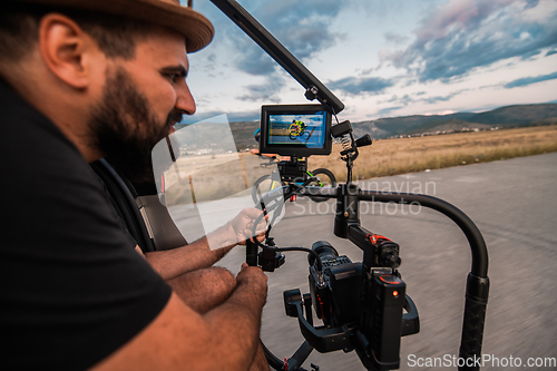 Image of A videographer recording a triathlete riding his bike preparing for an upcoming marathon.Athlete's physical endurance and the dedication required to succeed in the sport.