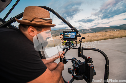 Image of A videographer recording a triathlete riding his bike preparing for an upcoming marathon.Athlete's physical endurance and the dedication required to succeed in the sport.