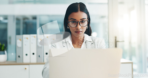 Image of Business woman, glasses and working on laptop in office for planning, reading email and internet research in law firm. Indian lawyer, attorney and focus at computer to start legal analysis in company