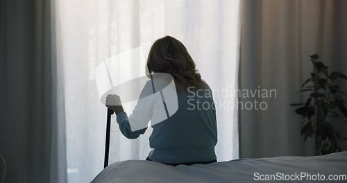 Image of Thinking, sad and window with old woman and walking stick in bedroom for wellness, retirement and healthcare. Depression, mental health and nursing home with patient with a disability for support