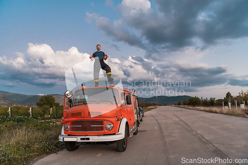 Image of The firefighter standing confidently on the fire truck, ready to respond to any emergency.