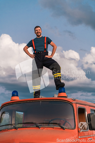 Image of The firefighter standing confidently on the fire truck, ready to respond to any emergency.