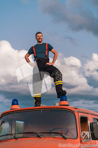 Image of The firefighter standing confidently on the fire truck, ready to respond to any emergency.