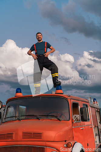 Image of The firefighter standing confidently on the fire truck, ready to respond to any emergency.