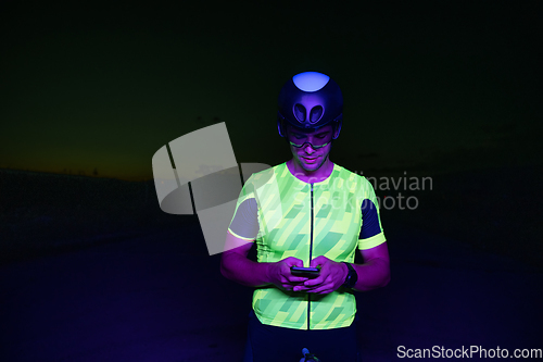 Image of A triathlete using a smartphone while taking a break from a hard night's cycling training