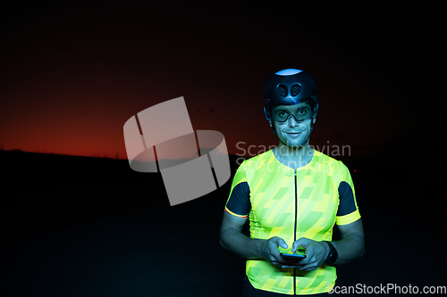 Image of A triathlete using a smartphone while taking a break from a hard night's cycling training