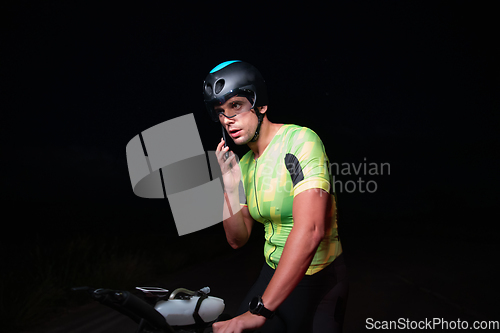 Image of A triathlete using a smartphone while taking a break from a hard night's cycling training