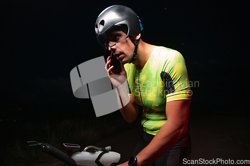 Image of A triathlete using a smartphone while taking a break from a hard night's cycling training