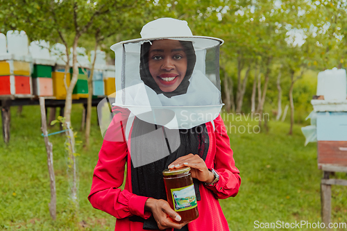 Image of Portrait of a Muslim investitor in the beekeeping department of a honey farm holding a jar of honey in her hand